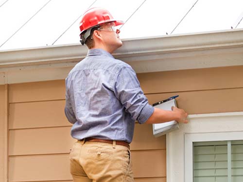 A building inspector checking the gutters of a house.